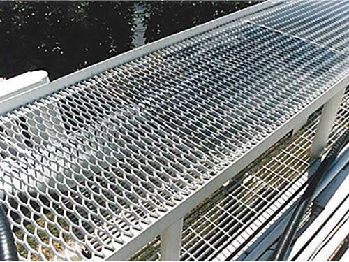 Regular expanded metal gratings with silver surface and hexagonal holes are installed on the walkways in the factory.